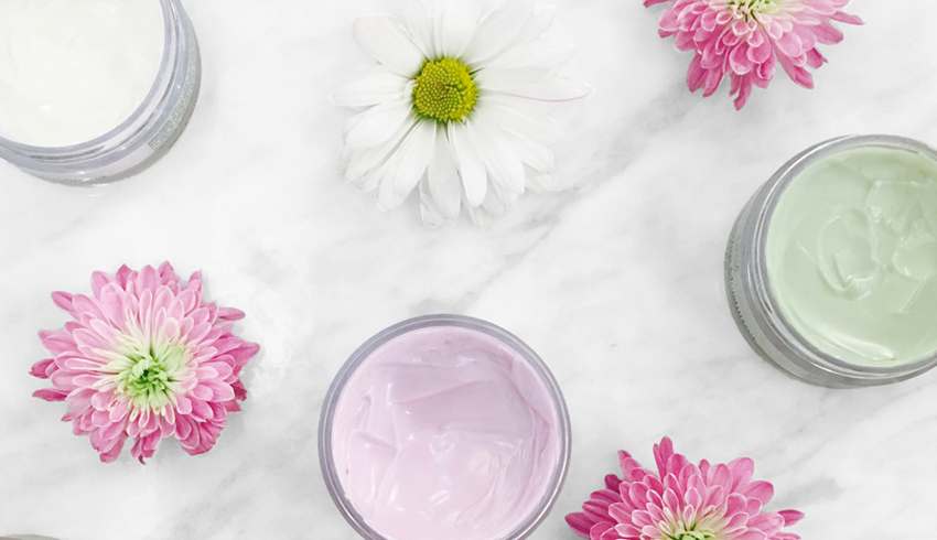 Flower heads placed around open skin care containers. 
